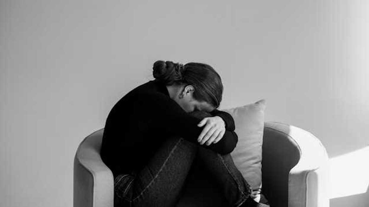 A person sitting in a chair with their head on their knees