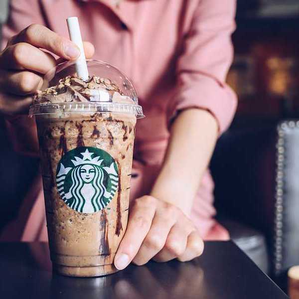 A person sitting in front of a plastic cup with starbucks logo on the side