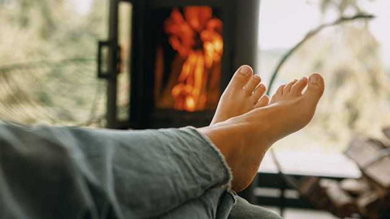 A person sitting in front of a woodstove