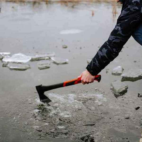 A person sitting on a dock breaking the ice on a lake
