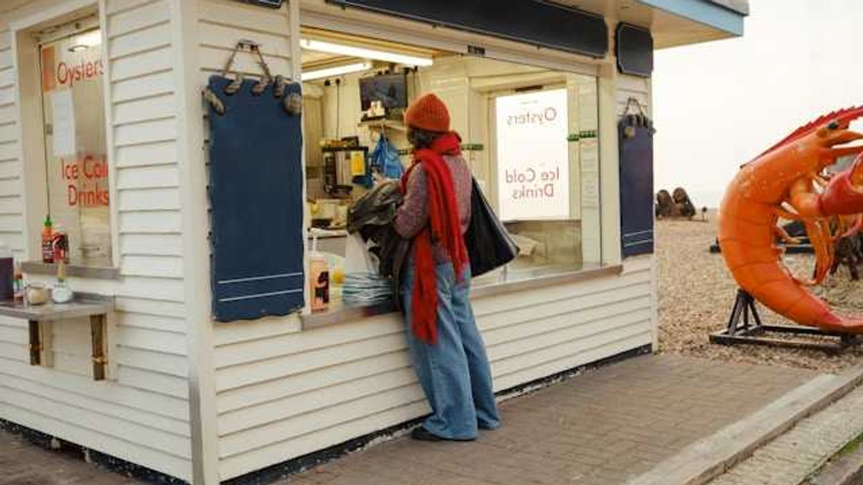 A person standing at an outdoor kiosk which sells oysters