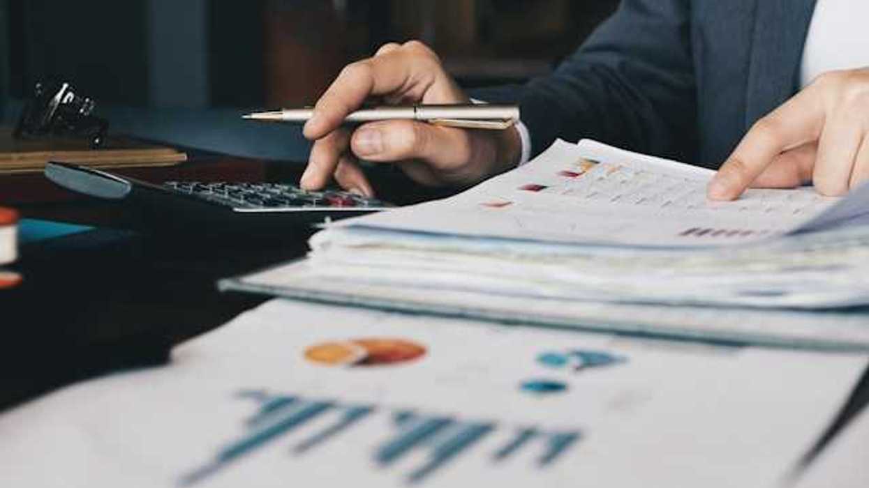 A person using a calculator to verify numbers on a financial document
