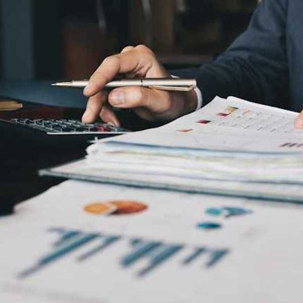 A person using a calculator to verify numbers on a financial document