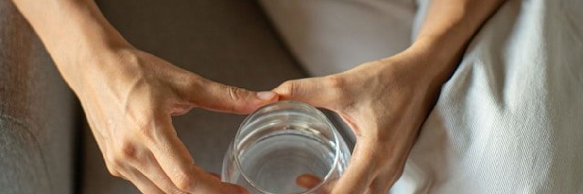 A person viewed from above holding a glass of water.