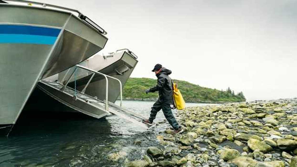 A person walking into a boat ramp off a rocky shore in the wilderness