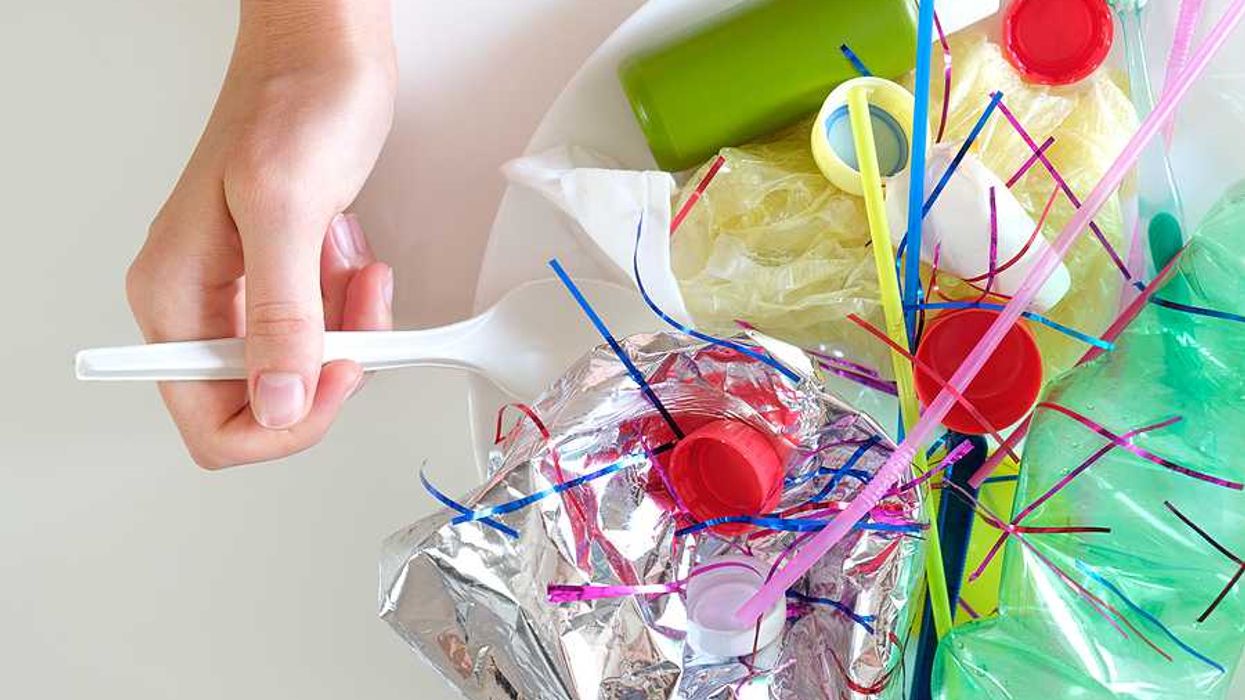 A person with a plastic spoon pretending to eat a meal of plastic items