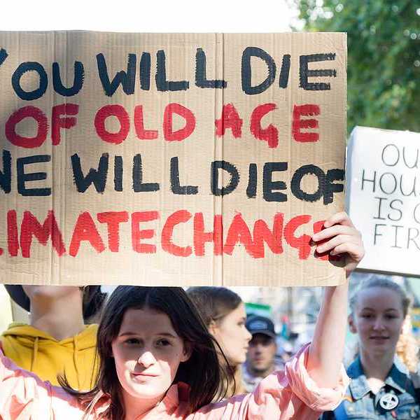 A person with a sign saying 'You will die of old age; we will die of climate change'