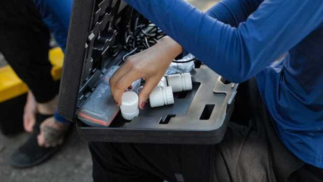 A person with a small case on their lap with water testing tools