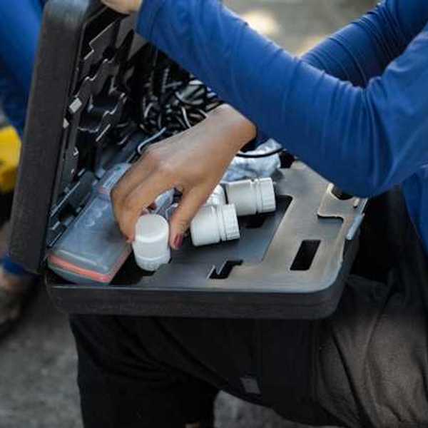 A person with a small case on their lap with water testing tools