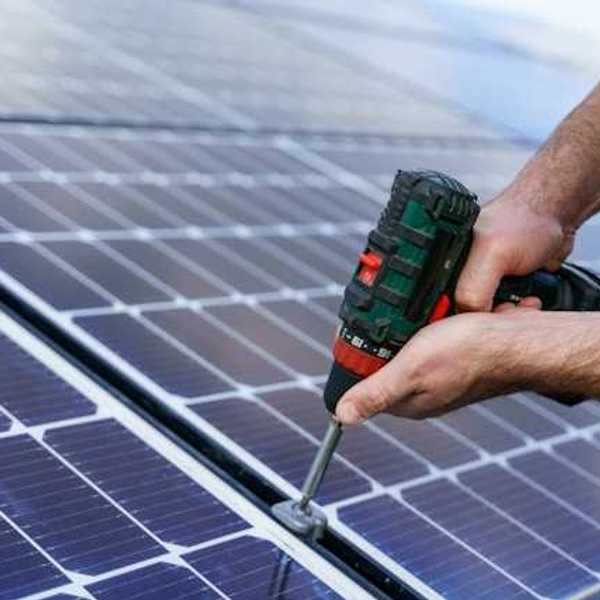 A person with cordless driver installing solar panels