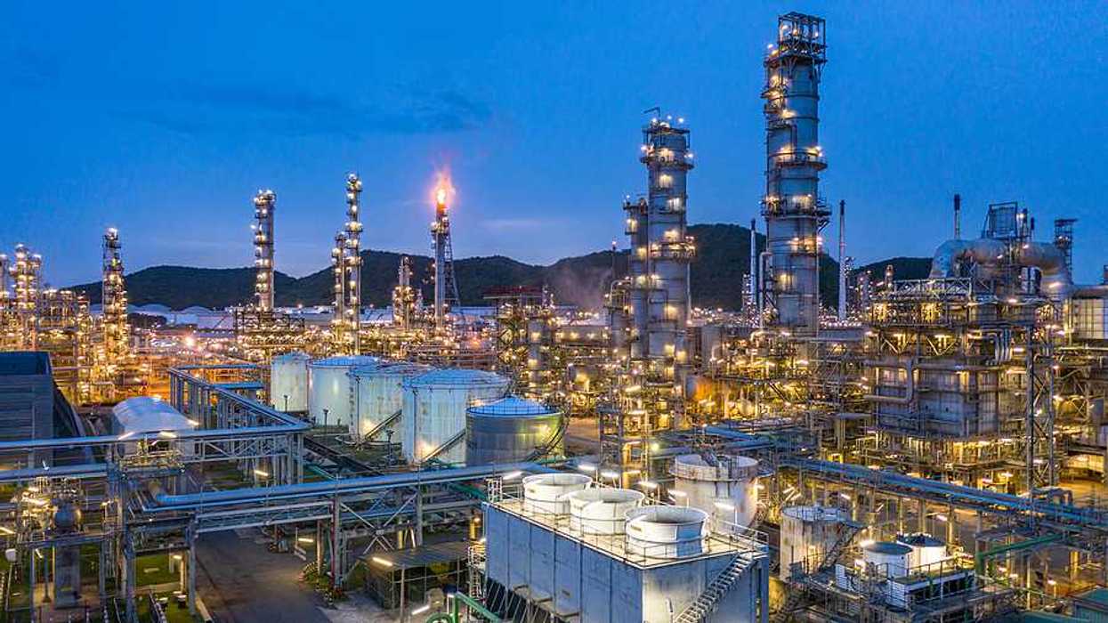 A petrochemical plant lit up at night with hills in the background