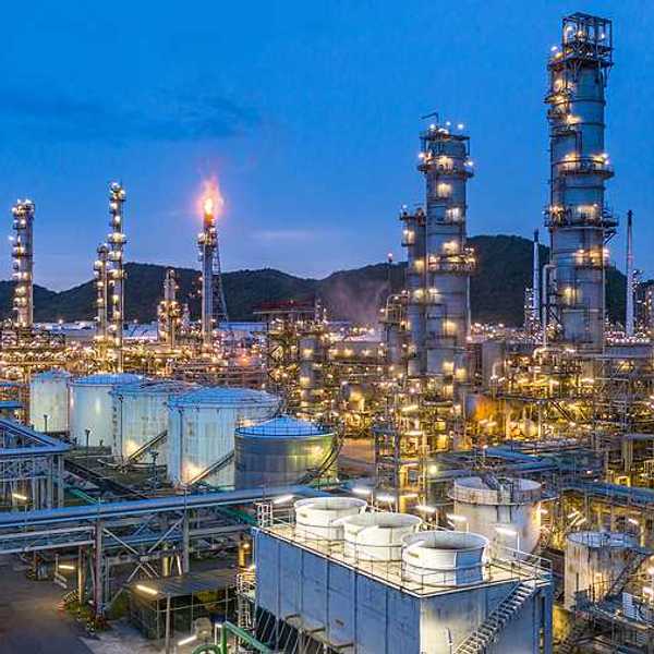A petrochemical plant lit up at night with hills in the background