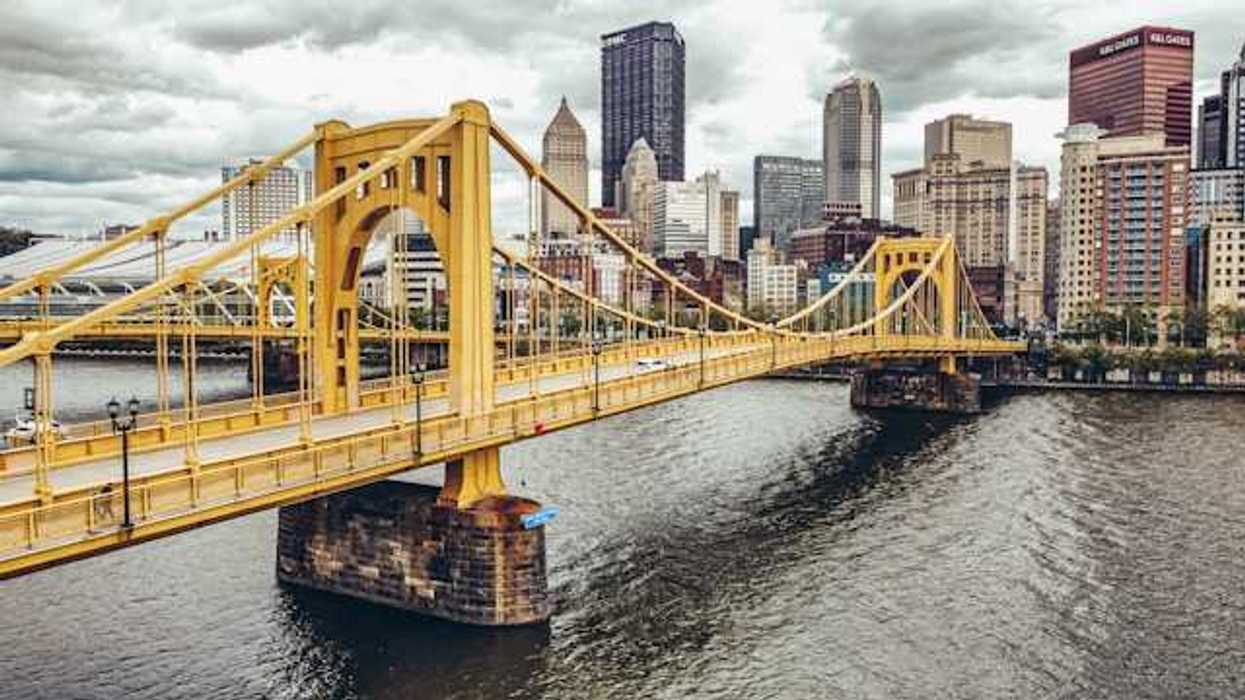 A photo of a yellow bridge crossing the river into downtown Pittsburgh