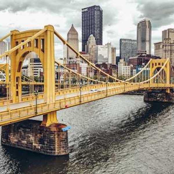 A photo of a yellow bridge crossing the river into downtown Pittsburgh