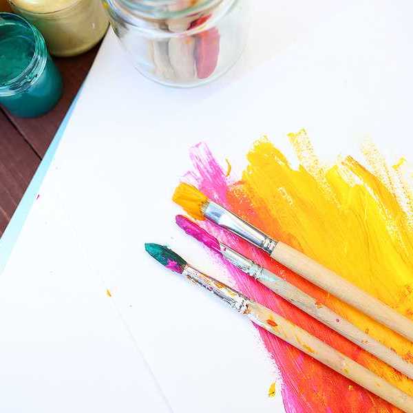 A piece of paper with paint on it along with paint brushes and pots of pain