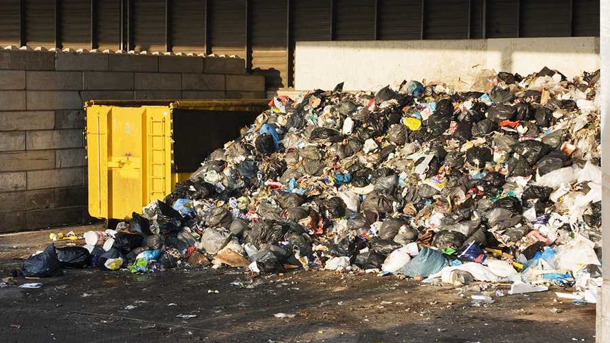 A pile of garbage next to a dumpster