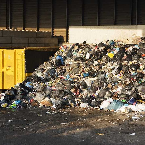 A pile of garbage next to a dumpster