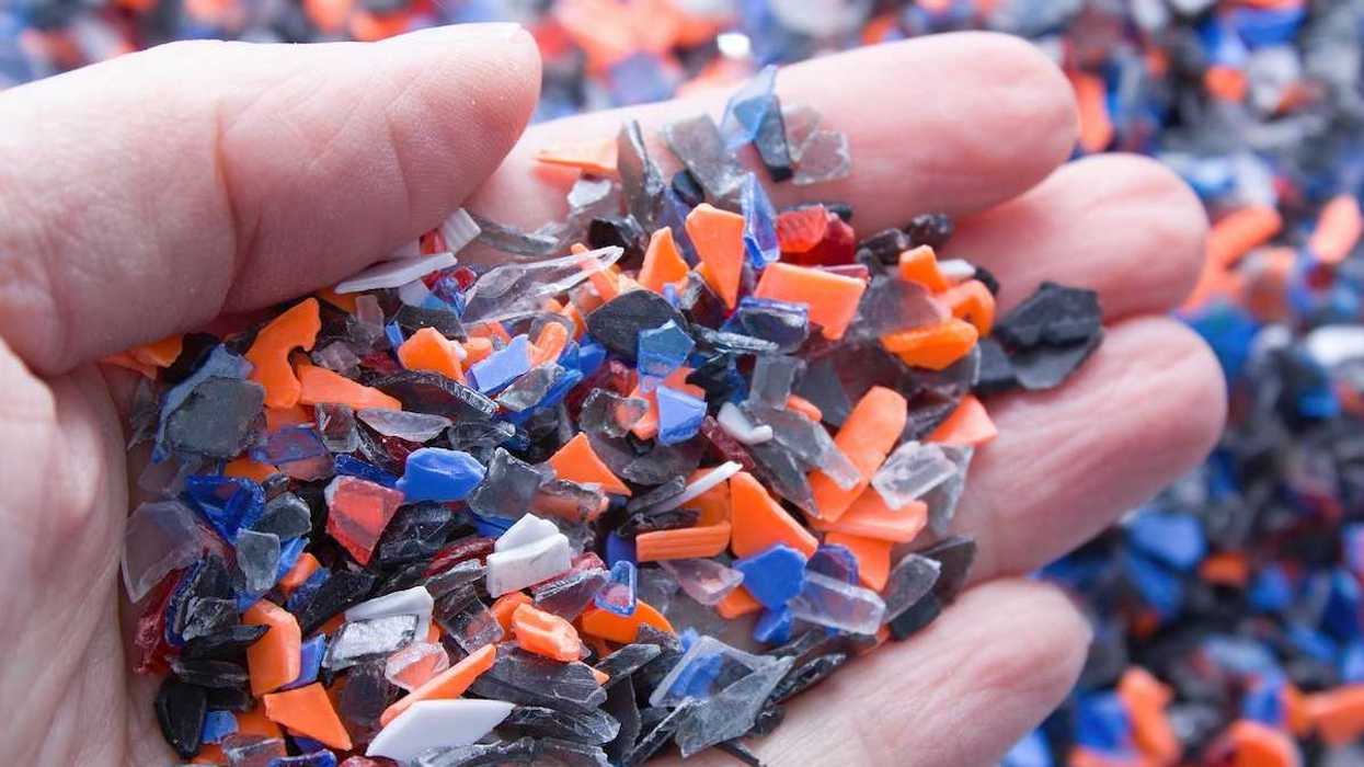 A pile of microplastics - small pieces of hard plastic on palm, intended for further processing.