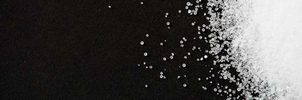 A pile of white granules similar to sugar on a black background