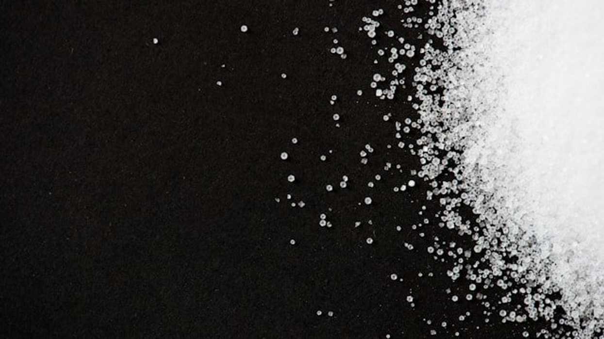 A pile of white granules similar to sugar on a black background