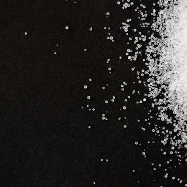 A pile of white granules similar to sugar on a black background