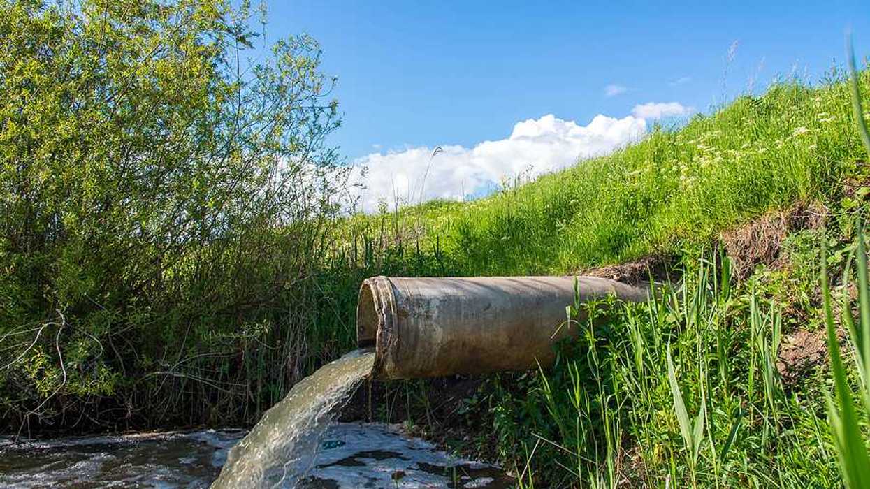 A pipe emitting water into a pond