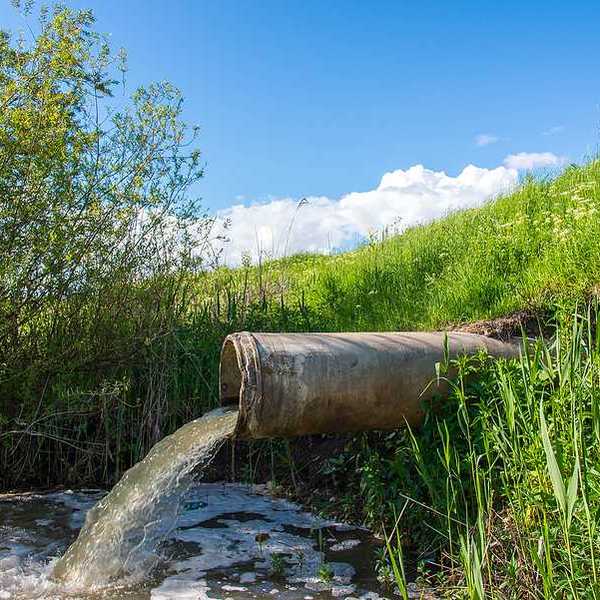 A pipe emitting water into a pond