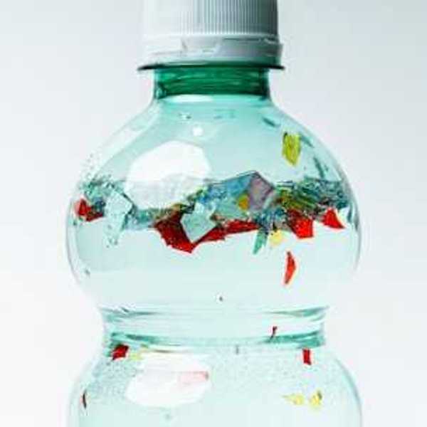 A plastic bottle with small bits of plastic floating inside of it