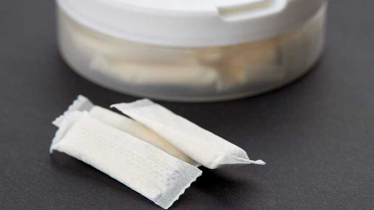 A plastic container with small white pouches on a black background