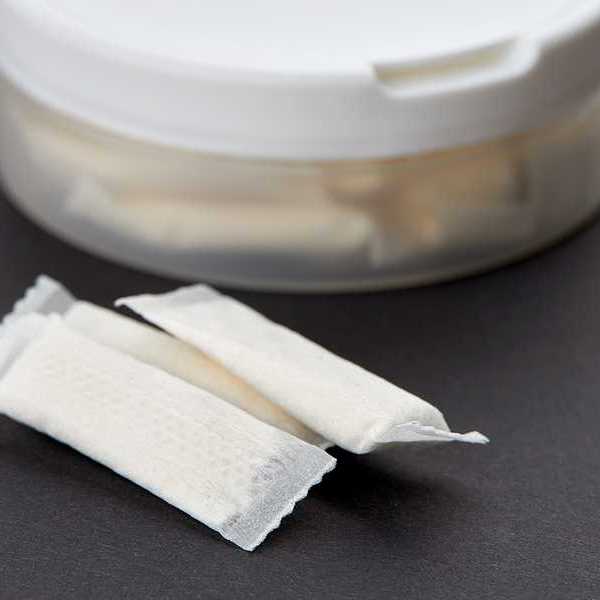 A plastic container with small white pouches on a black background