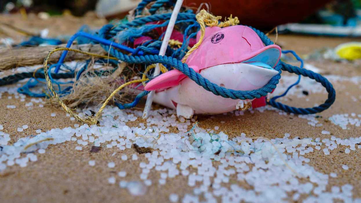 A plastic toy sitting near plastic nurdles on a sandy beach