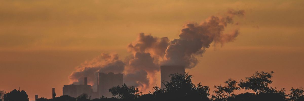A power plant in the distance with smoke arising from towers