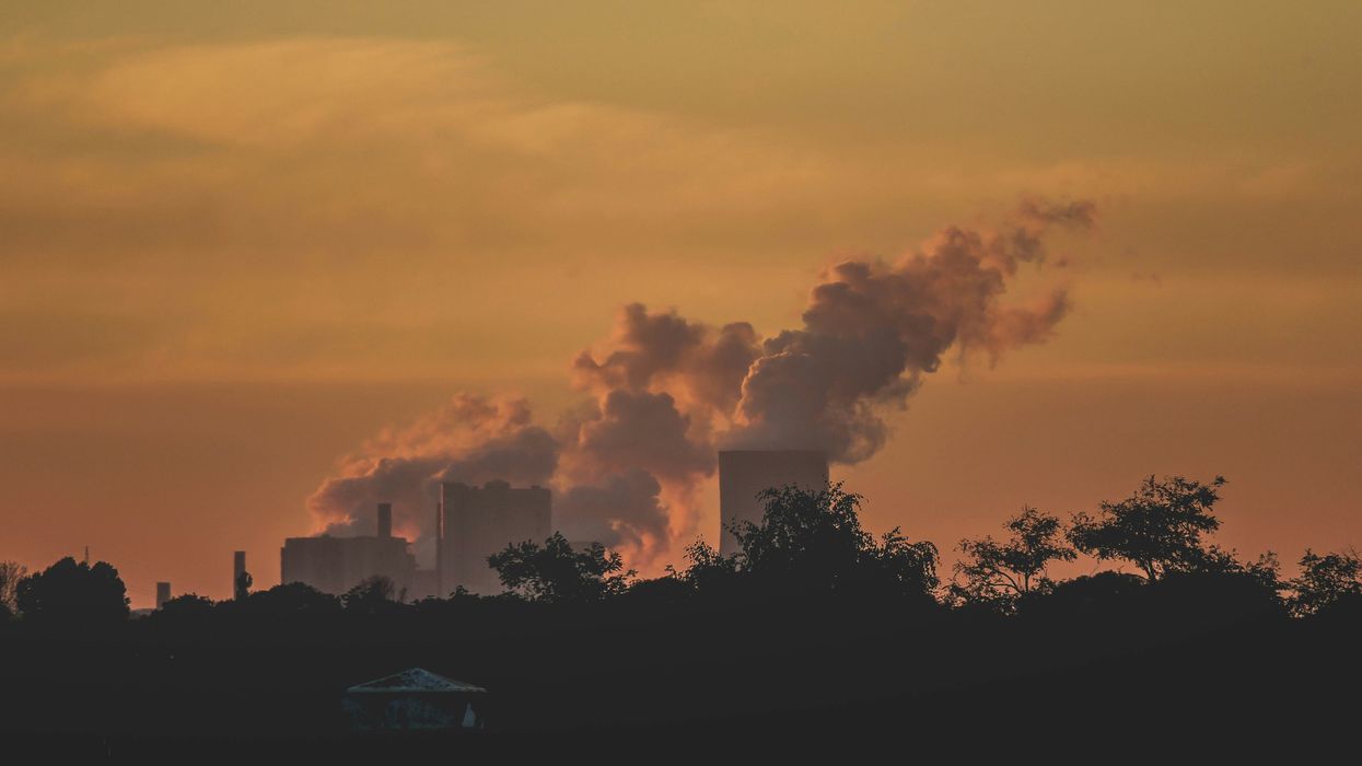 A power plant in the distance with smoke arising from towers