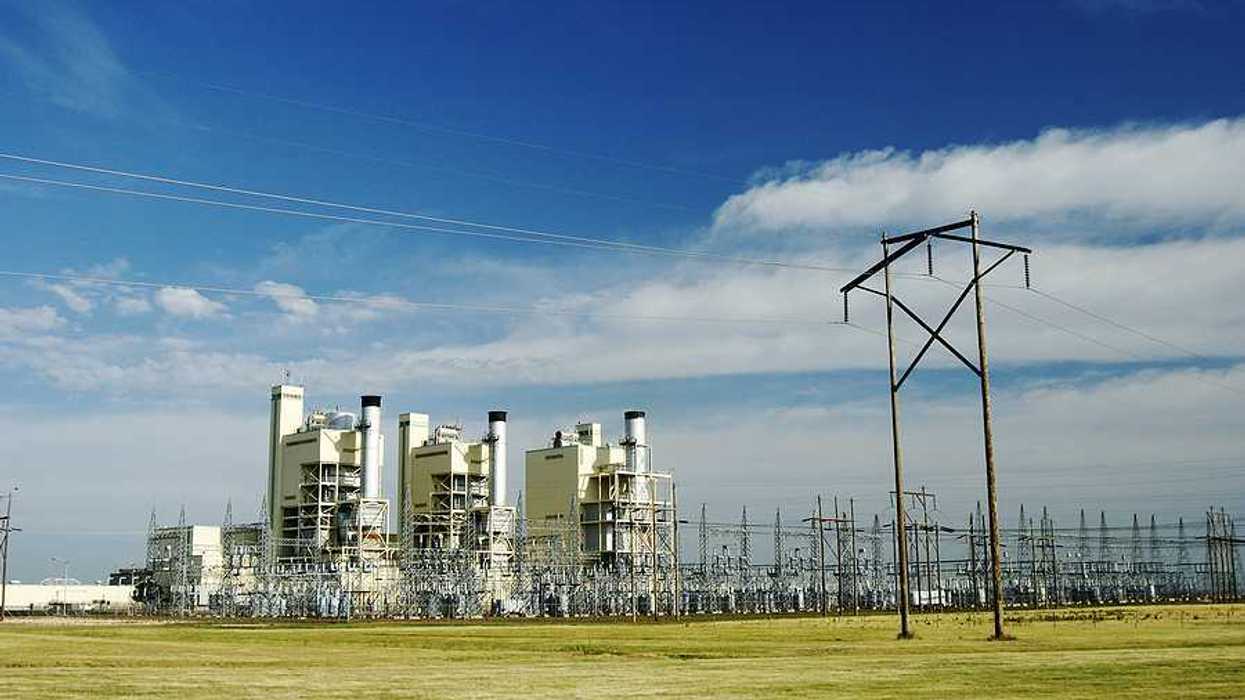 A power plant on a sunny day with a field in the foreground