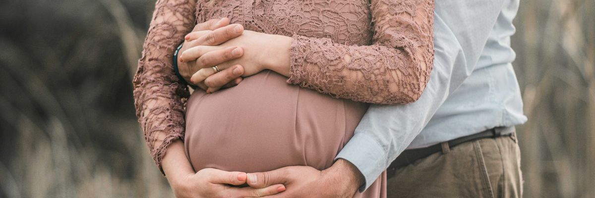 A pregnant couple with hands interlaced