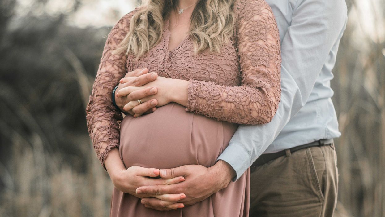 A pregnant couple with hands interlaced