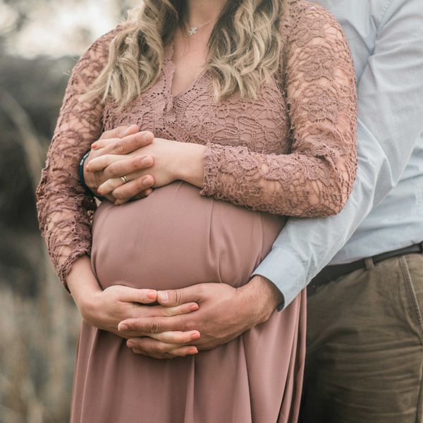 A pregnant couple with hands interlaced