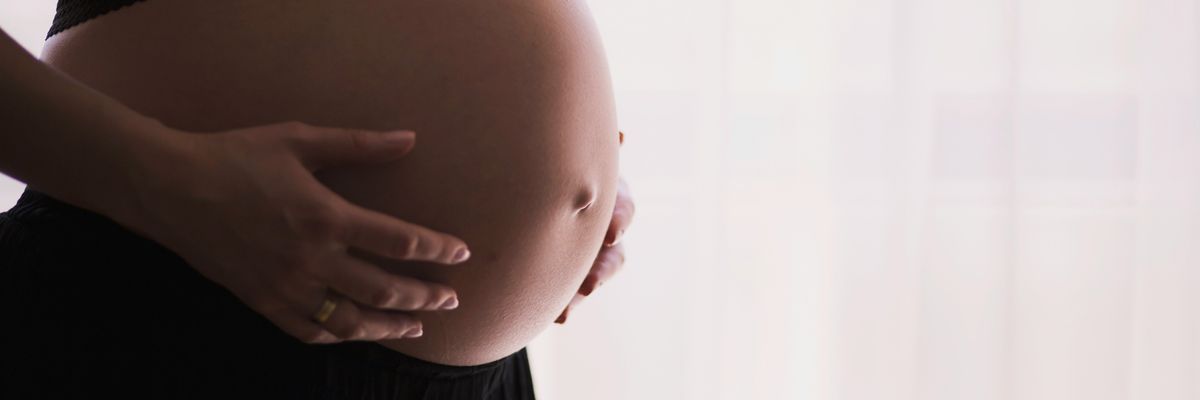 A pregnant woman against a white backdrop
