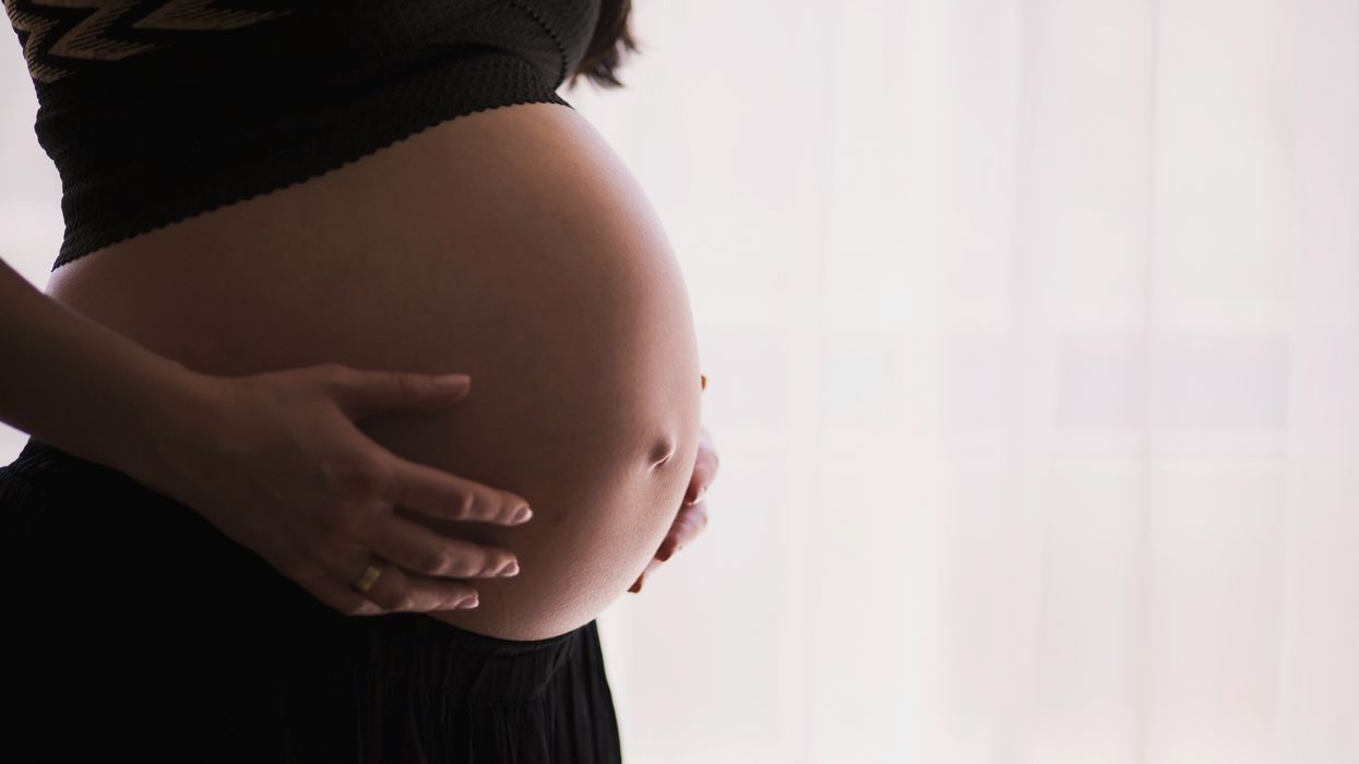 A pregnant woman against a white backdrop