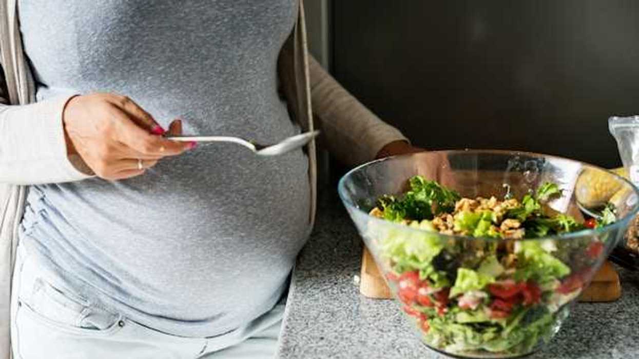 A pregnant woman eating salad out of a bowl