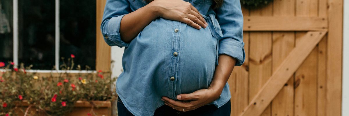 A pregnant woman in front of a home