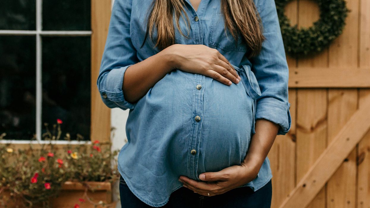 A pregnant woman in front of a home