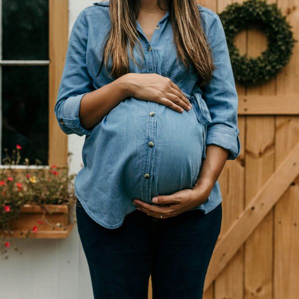 A pregnant woman in front of a home
