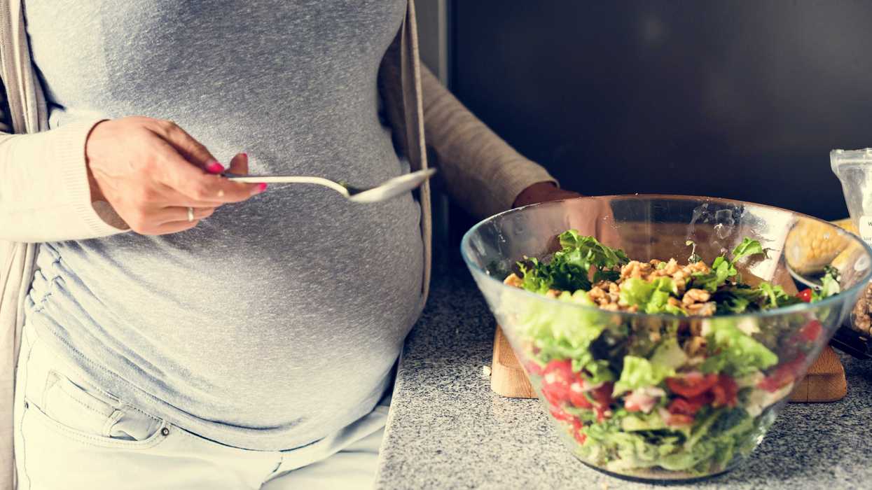 A pregnant woman prepares a salad