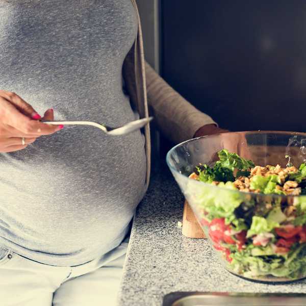 A pregnant woman prepares a salad