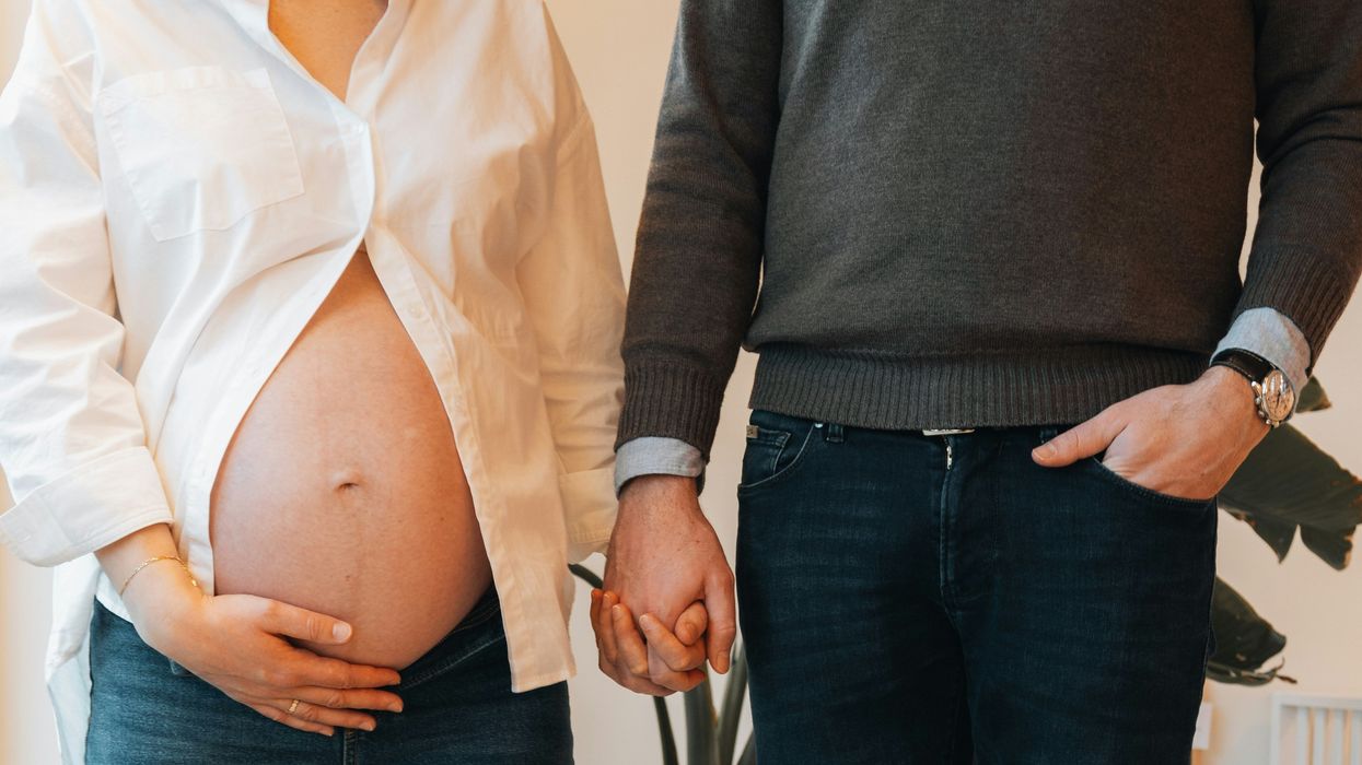 a pregnant woman standing next to a man