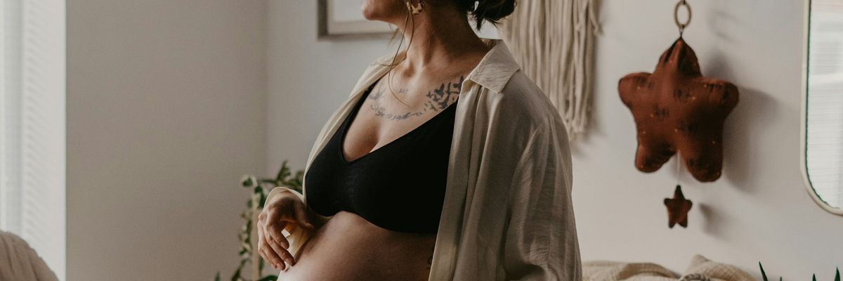 A pregnant woman stands in a nursery
