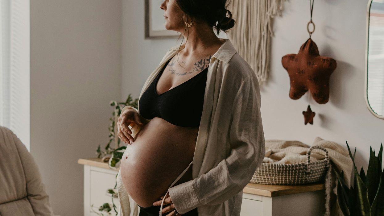 A pregnant woman stands in a nursery