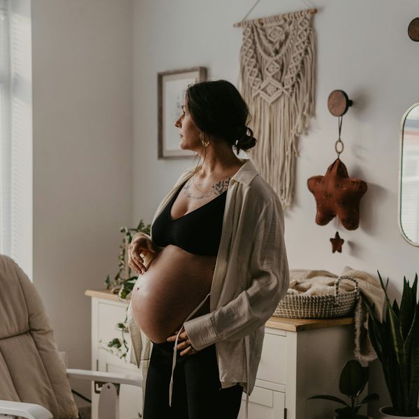 A pregnant woman stands in a nursery