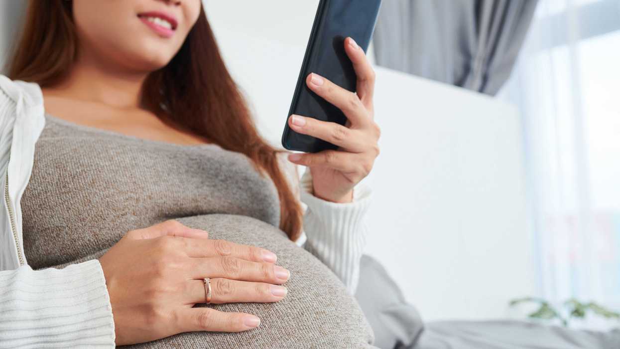 A pregnant woman uses a cell phone